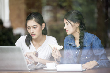 Asian Woman using Laptop for Seach Information at Cafe Together, Woman Talking with Friend while using Laptop, Woman Lifestyle Concept.