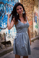 A beautiful girl posing beside the rustic wall, and painted with graffiti