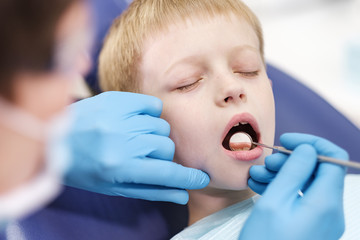 Male dentist examines the teeth of the patient cheerful boy.