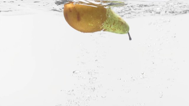 Pear plunging into water on white background