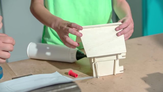 A couple of boys are designing a wooden house in a craft class. Later, they will also colour it. 