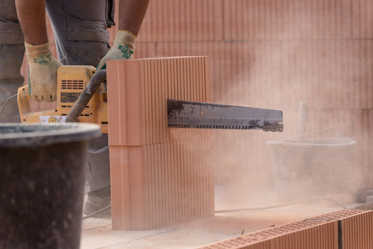 Auf der Baustelle wird ein Ziegel mit der S&auml;ge geschnitten