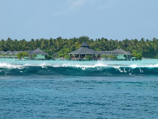 Fototapeta na wymiar Water villas of Maldives Islands with big ocean waves