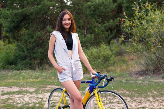 Young woman stands with a bicycle on a forest road