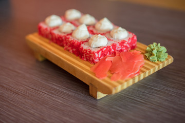 Japanese food on a wooden plate of sushi rolls with fish and rice, ginger and green wasabi