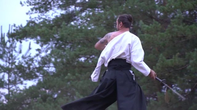 A samurai with a tattoo beautifully unwinds a heavy halberd to strike on top of a samurai with a katana, slow motion