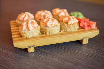Japanese food on a wooden plate of sushi rolls with fish and rice, ginger and green wasabi