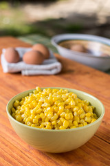Cooked corn in the bowl with cooked eggs in the background