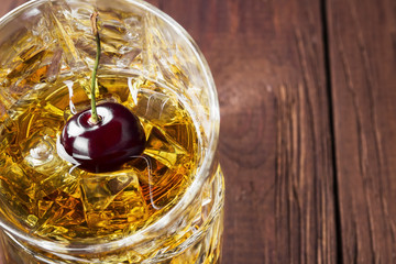 Cocktail from whisky with cherry in two glasses on a wooden background. Copy space. Food background