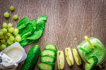 Green smoothie with apples, yogurt, spinach, cucumber on wooden background