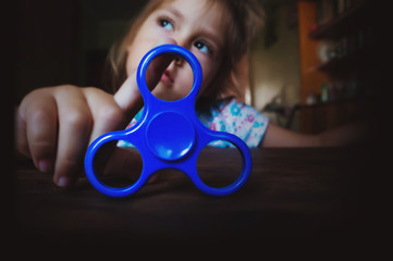 Little beautiful girl in is playing yellow spinner in hand