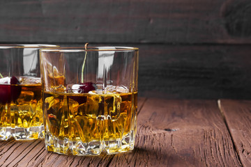 Cocktail from whisky with cherry in two glasses on a wooden background. Copy space. Food background