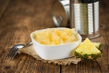 Portion of Chopped Pineapple (preserved) on wooden background, selective focus