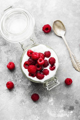 Glanola in glass jar with raspberry on a gray background. Top view. Food background