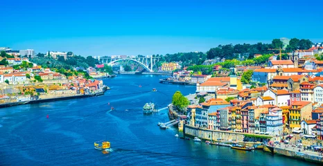 Fotobehang Beautiful panoramic view over Dom Luis I bridge and traditional boats on Rio Douro river in Porto, Portugal © cristianbalate