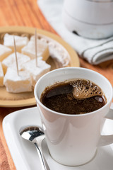 White cup of coffee with turkish delight in the background