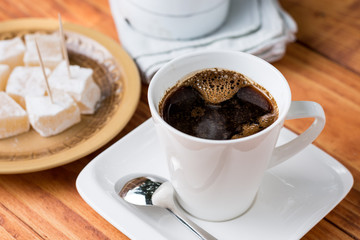 White cup of coffee with turkish delight in the background