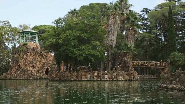 Beautiful pond in Sama Park, Spain CAMBRILS, SPAIN - SEPTEMBER 24, 2016: Peaceful view at pond with bridge and islands in Sama Park under blue sky, Catalonia
