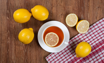 Still life of fresh lemons on a wooden table with cup of tea