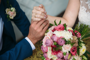 Closeup groom and bride are holding hands at wedding day and show rings. Concept of love family