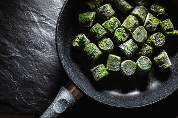 Frozen spinach in briquettes in a frying pan