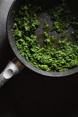 Fototapeta na wymiar Roasting the chopped spinach leaves in a frying pan