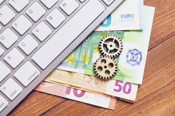 Detail of a gear, euro banknotes and keyboard
