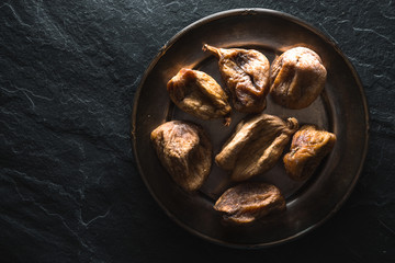 Dry figs on a tin plate on a gray stone closeup