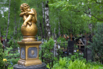 Fototapeta na wymiar little angel sit on the ball on cemetery