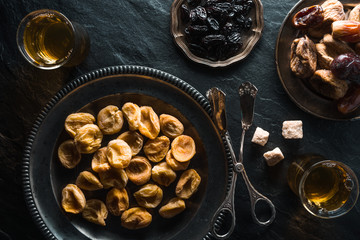 Dried apricots, dates and raisins on metal plates on a gray table
