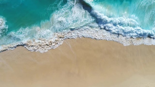 Aerial drone footage of ocean waves reaching shore. Beach on aerial drone. Beach on top view. Beautiful beach. Beach clean.  Beach sea from Kelingking Beach in Nusa Penida, Bali, Indonesia.