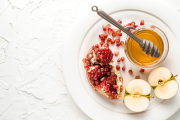 Pomegranate seeds, apples with honey on a ceramic plate