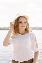 Portrait of a beautiful young blonde girl in hat, outdoors