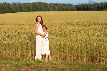 Mom and daughter are hugging in the summer on a wheat field