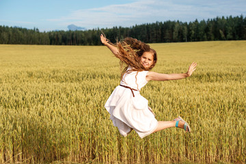 Naklejka na ściany i meble Girl in flight from a jump on a wheat field in summer
