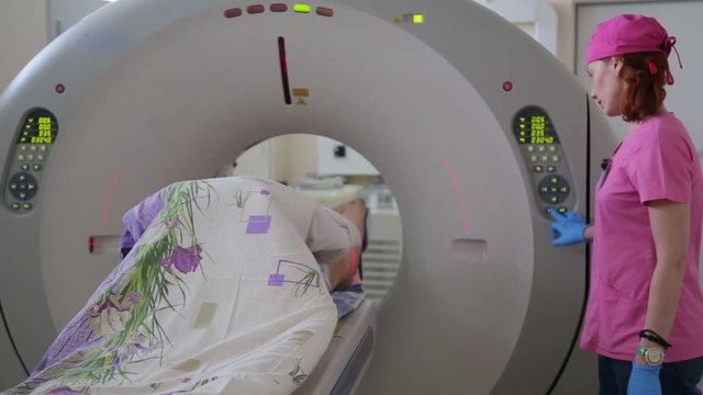 The doctor conducts a medical examination of the patient using a tomographic device. Tomography