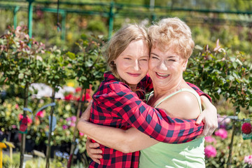 Grandmother and granddaughter hugging in a garden.
