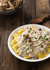 Plate of ravioli with cream sauce on wood table