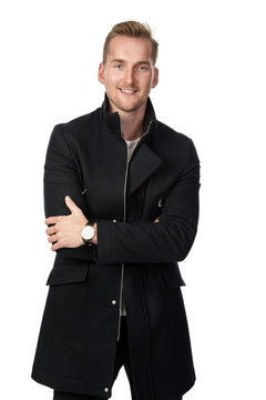 Handsome man wearing a trenchcoat standing with his arms crossed looking at camera against a white background.