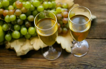 Fotobehang Two glasses and grapes in a decorative basket on a wooden surface. © Михаил 
