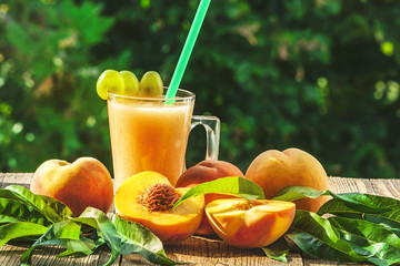 Bright peaches. Peach smoothies. Green blurred background.