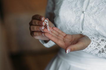 Earrind in the hands of the bride. Concept of jewelry