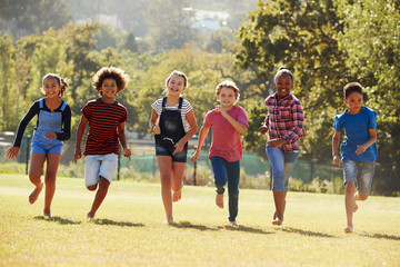 Six pre-teen friends running in a park, front view, close up