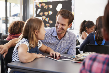 Teacher and schoolgirl using tablet looking at each other