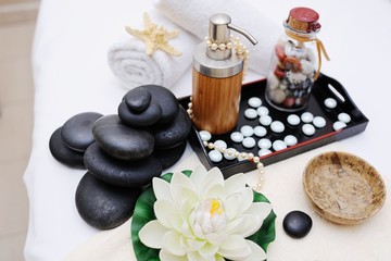 Fototapeta na wymiar stones for massage , massage oil and a flower in Spa salon