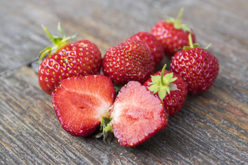 Group of fresh red strawberries on wooden table. Clean, delicious and ready to eat. Halved fruit.