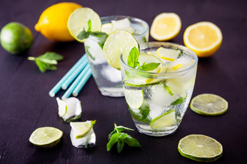 Refreshing drink with crushed ice and lime with lemon on dark background