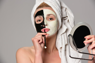 beautiful female model with facial cosmetic mask posing. Isolated on gray background.