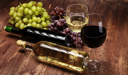 Obraz premium Red Wine bottle and white wine with grapes and glasses on wooden background