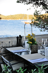 Nakryty stół restauracyjny na zewnątrz, z widokiem na morze i wyspy w Chorwacji.